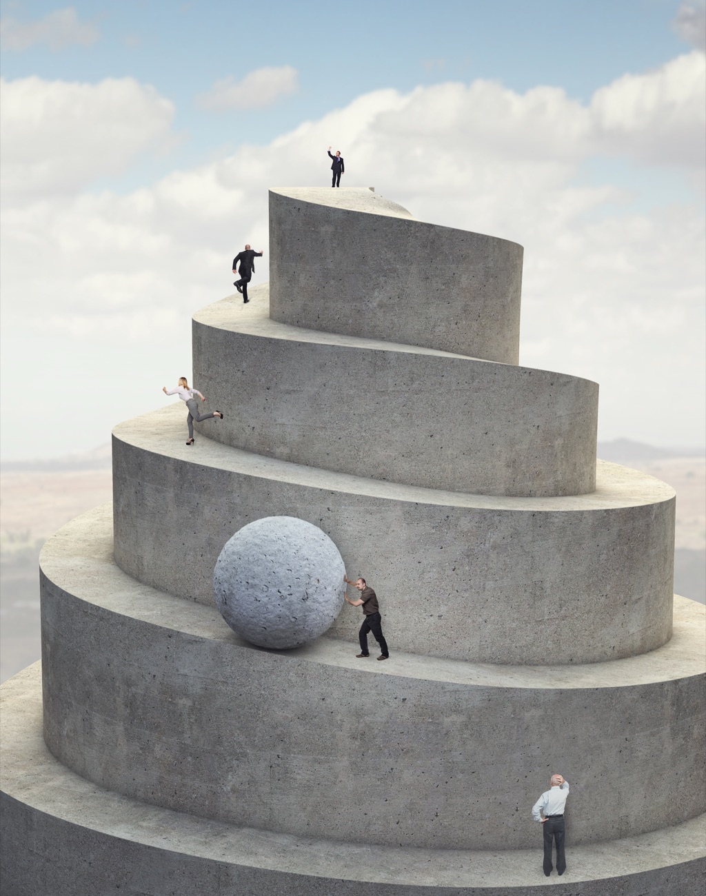 Menschen steigen einen spiralförmigen Betonturm hinauf, einer rollt eine Steinkugel nach oben